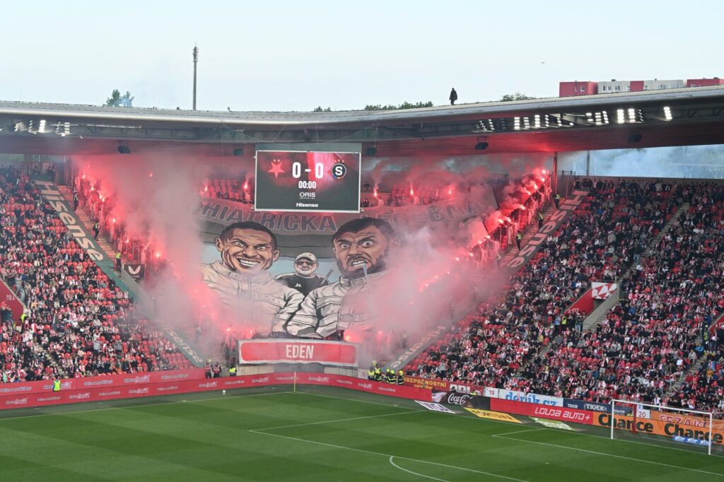 Karikatura slavistických fotbalistů viděných sparťanskými fanoušky lemovaná světlicemi