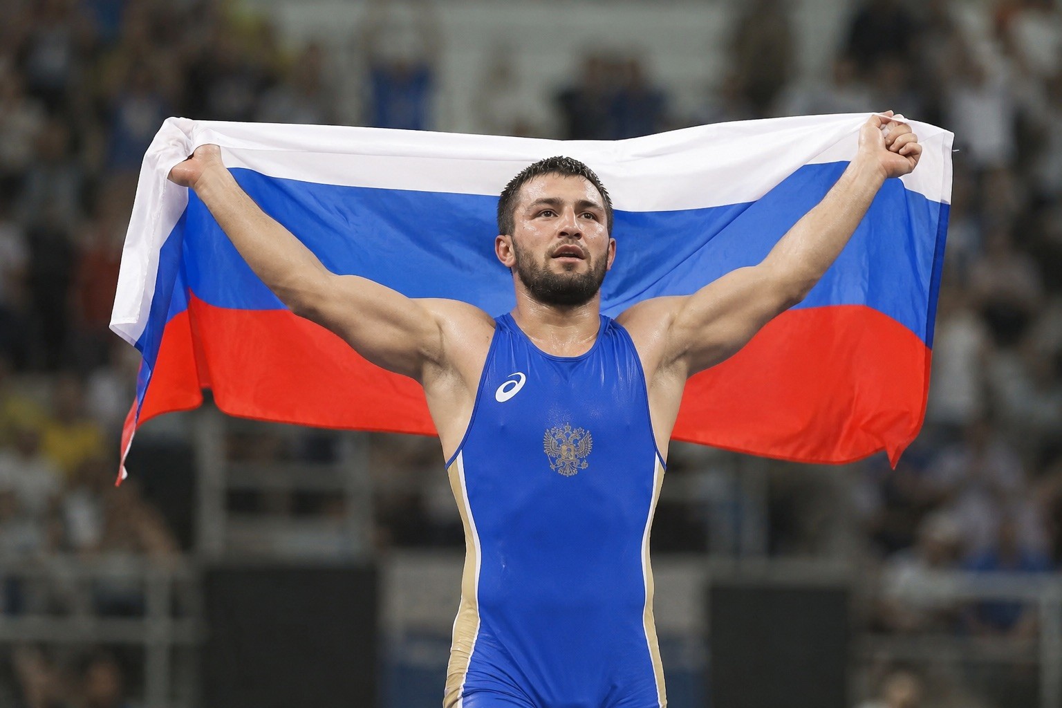 Ruský zápasník Davit Čakvetadze oslavuje vítězství na olympijských hrách v Riu 2016 s národní vlajkou.
